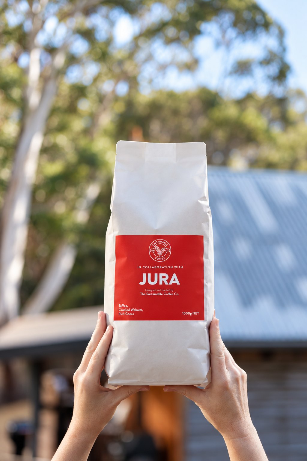 Jura bag held up in front of a timber cabin